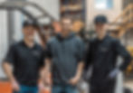 Trois hommes souriants se tiennent debout dans l'entrepôt Rotorap