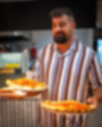 Pizza chef in striped shirt serves 2 traditional Italian pizzas