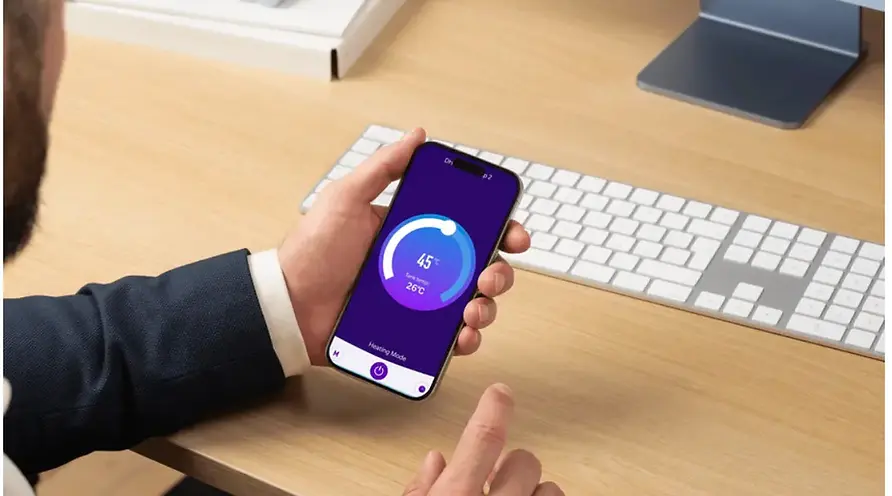 Image of a person looking at his phone which has the delta green heat pump IoT app