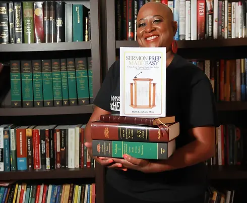 Sherri Jackson holding a stack of books in front of bookshelves