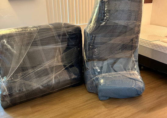 Professional movers wrapped sofas with moving pads, plastic wrap and tape.