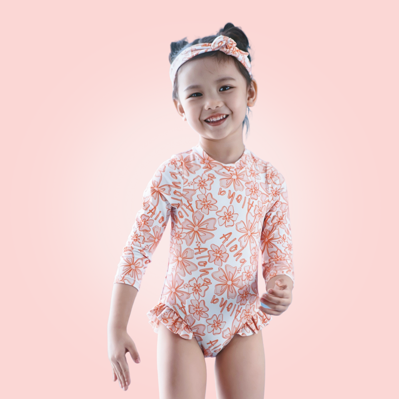 Baby girl modeling long-sleeve rashguard, premium kids swimwear with cute aloha design