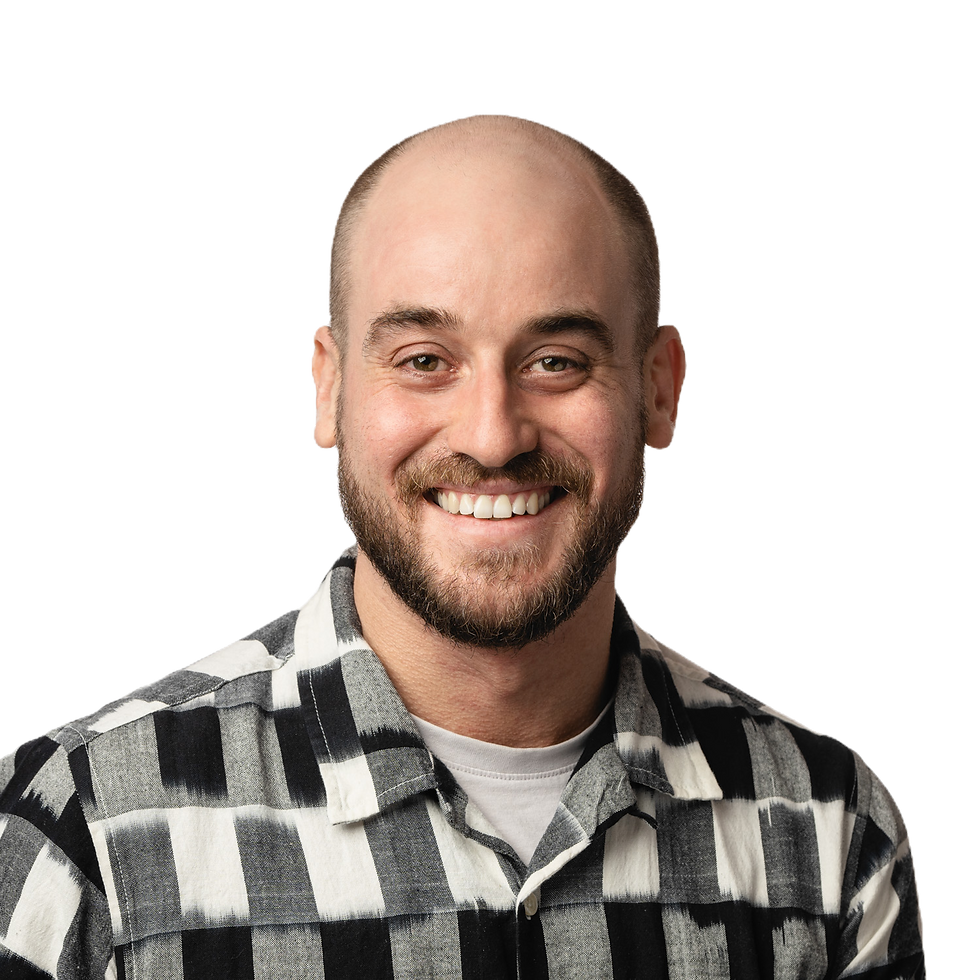 Headshot of Nick Peel. He has a shaved head and beard and is wearing a black, white and grey checked shirt