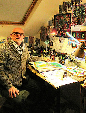David Grimbleby working in his studio on artwork, with pencils, paints and lamps on the worktop