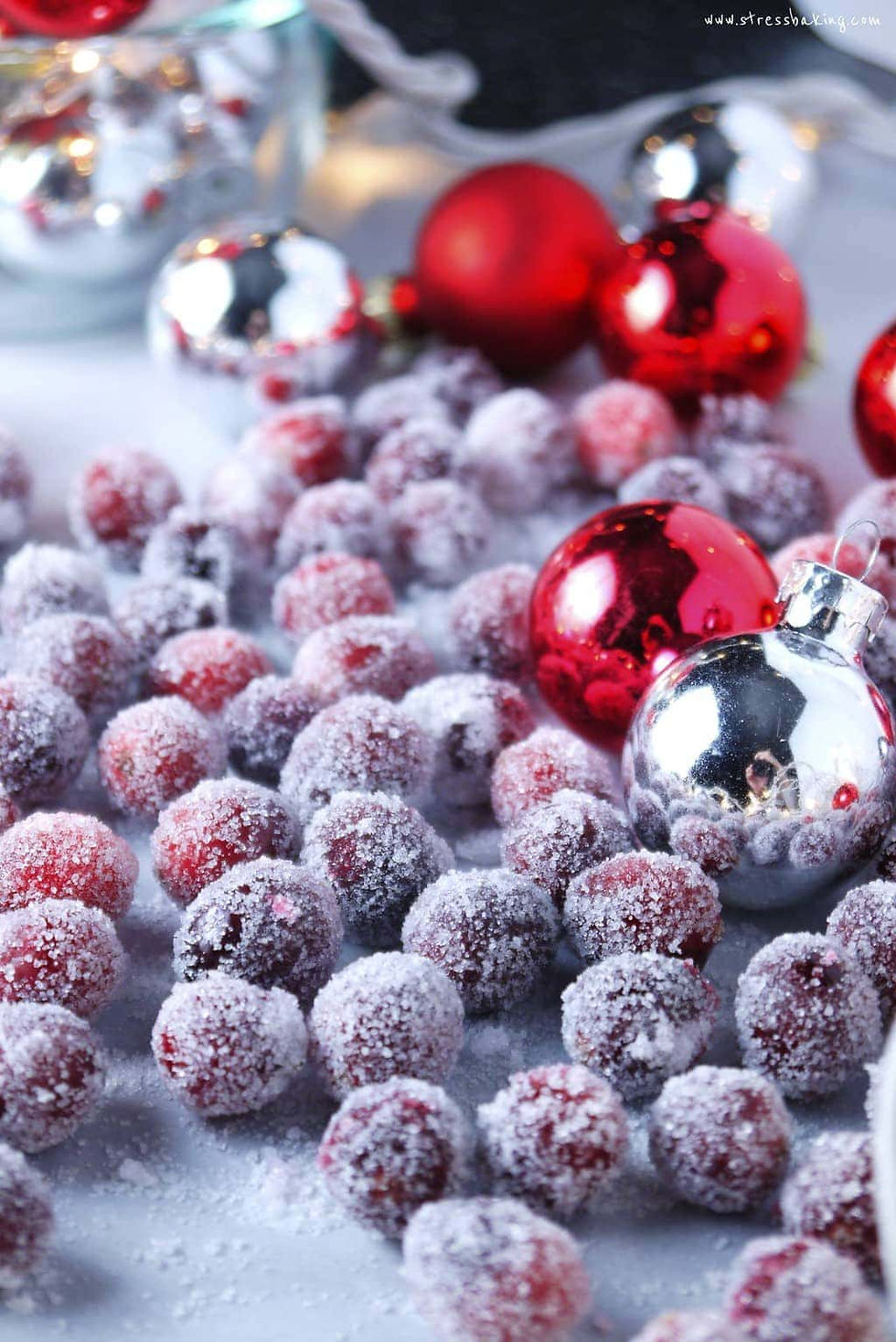 sugared cranberries on a table with silver and red christmas ornaments