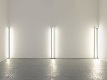 a wall with florescent bars. One bar in the left corner, two bars together in the center of the wall, and three bars together in the right corner