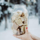hands holding a glass jar full of square soap bars in the snow