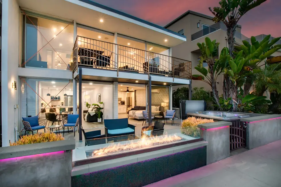 Modern luxury home exterior with glass walls and fireplace at twilight showcasing contemporary design