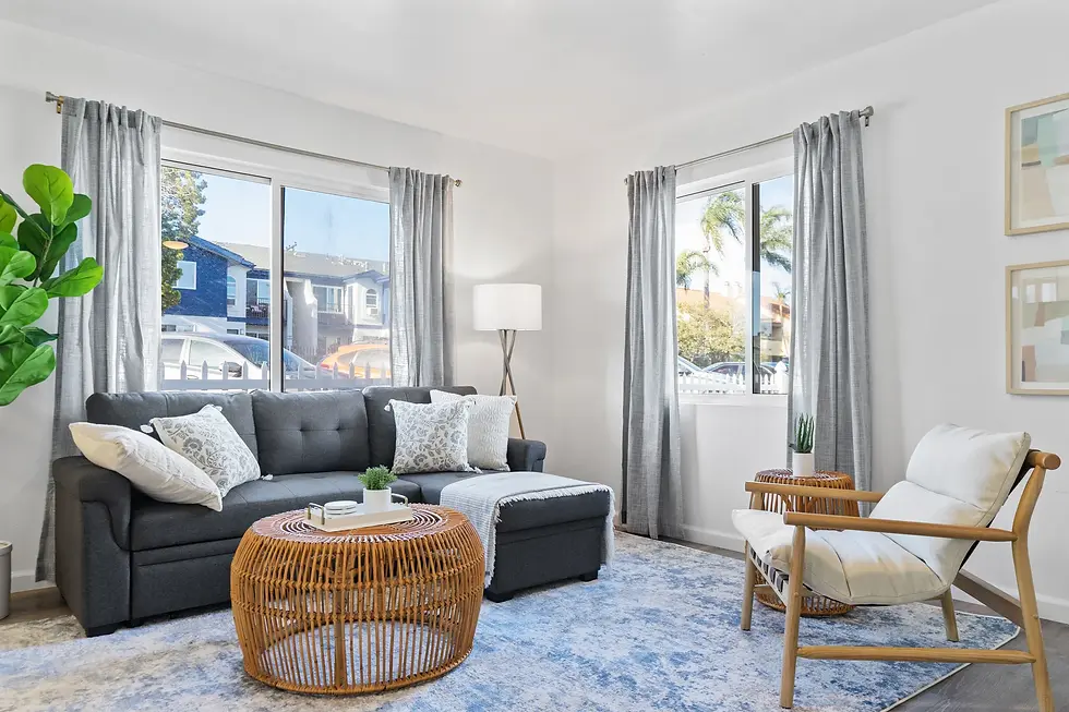 Bright living room with gray sectional sofa and rattan ottoman in a San Diego vacation rental with natural light