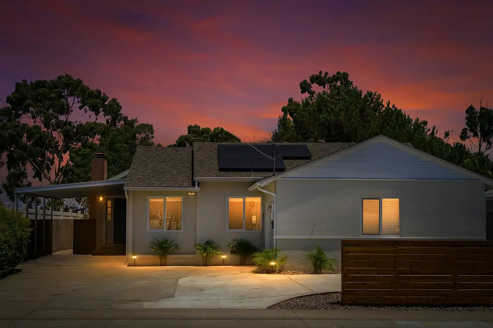 Modern San Diego home exterior at twilight with solar panels and warm lighting showcasing professional property management