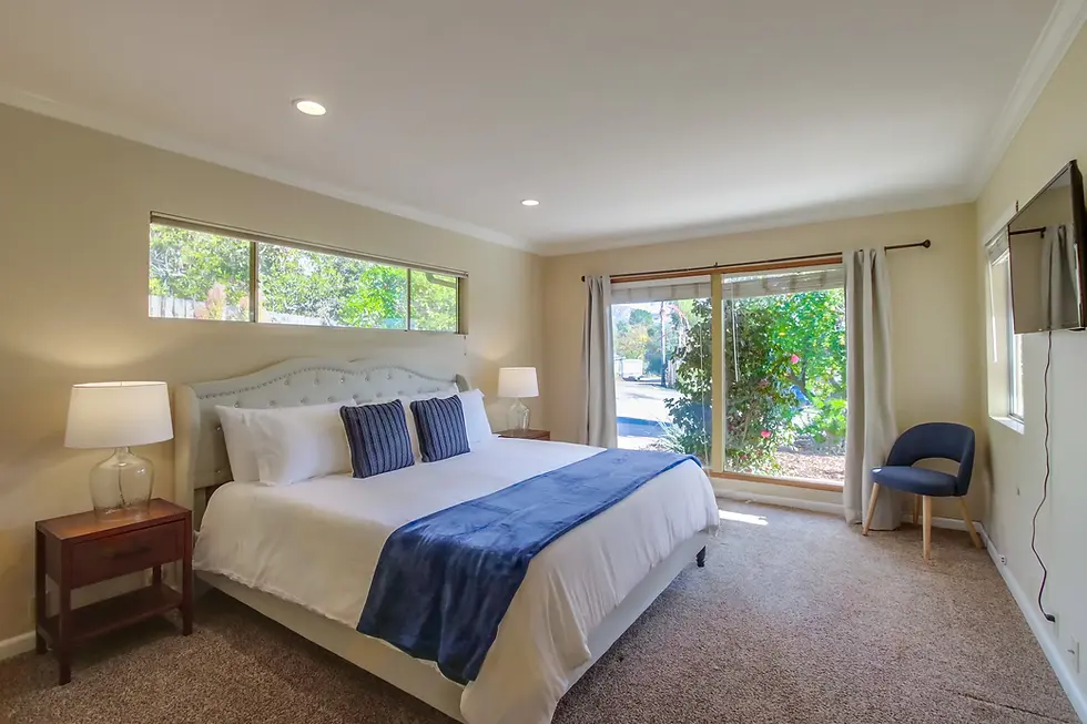Bright master bedroom in San Diego STR property with king bed, natural light, and garden views through sliding glass doors