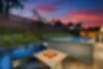 Modern San Diego backyard pool with fire pit seating area and sunset views, representing luxury vacation rental amenities