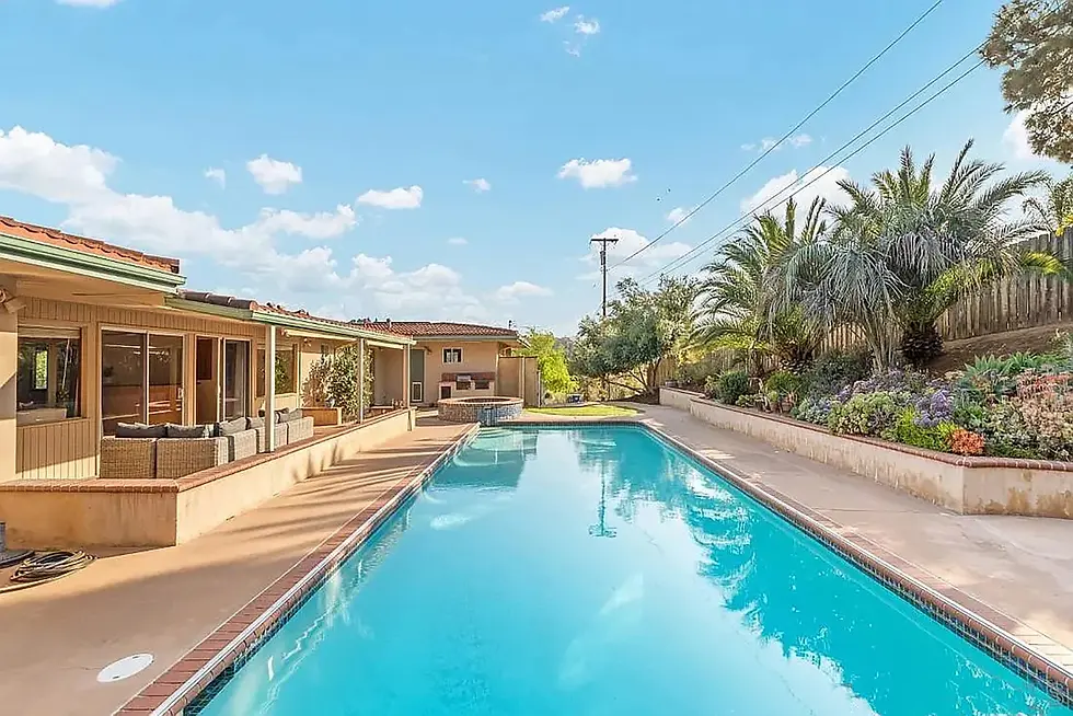Resort-style backyard with crystal-clear swimming pool and tropical landscaping at San Diego California property management