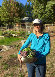 Jennifer standing on a farm with a bowl full of grapes.