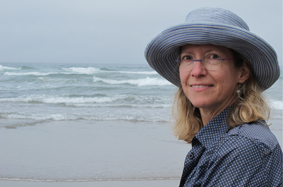 Jennifer standing on a beach with waves in the background