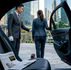 Chauffeur greeting businesswoman at luxury car