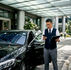 Chauffeur checks phone beside car outside office