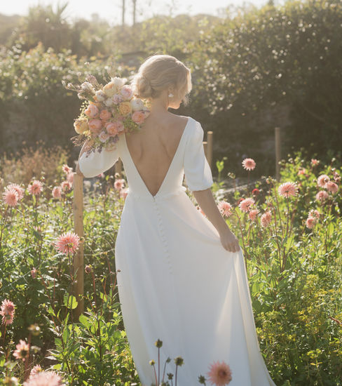 Discover Rosa by Sophie Rose Bridal, a sustainable wedding dress featuring a boat neckline, romantic puff sleeves, gathered lace detailing and a low V-back. Crafted from recycled fabrics for the modern bride.