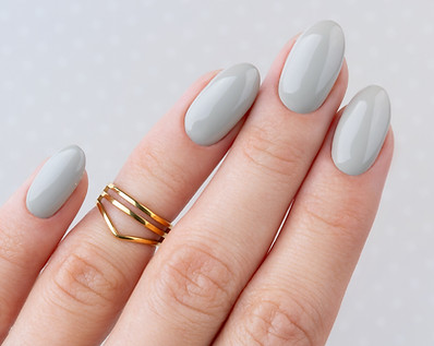 Beautiful womans hand with manicure close up on polka dot background. Gray nail polish. Be