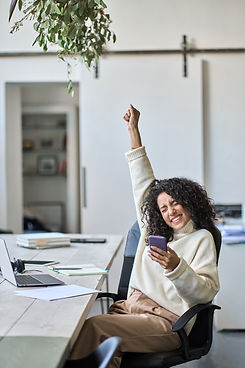 Euphoric young female worker holding mobile phone celebrating win receiving good news abou