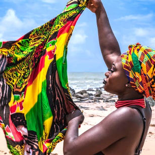 A Ghanaian woman in a Kente scarf waving a Ghana Flag at the beach