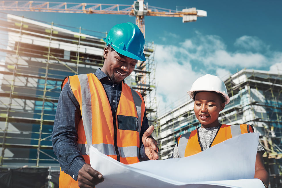 Two construction workers in hard hats review a blueprint at a sunny building site with scaffolding and a crane.