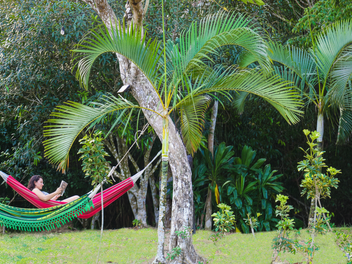 mujer leyendo libro en hamaca en el campo lleno de naturaleza arboles y verdor tranquilidad en su lote en Valle Miraflores, Panama