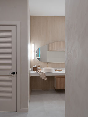 Spa bathroom sink area at Project RRR with asymmetrical mirror, round bowl sink, limewash walls, and minimalist accessories, designed to create a tranquil and elevated spa experience with natural textures.