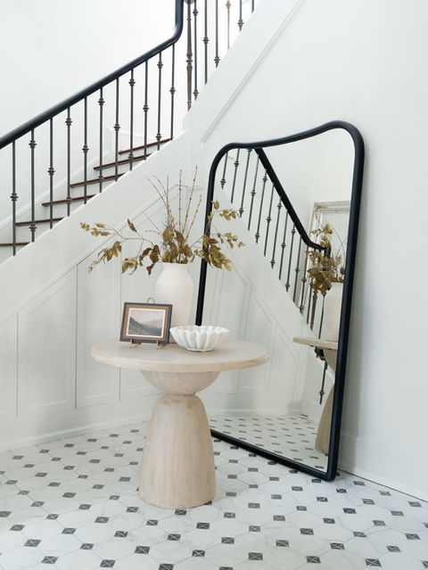 Project Pheabs entryway in Inman Park, Atlanta, GA with white checkered tile, large floor mirror, iron wrought staircase railings, and white walls, blending Parisian and Asian-inspired luxury interiors.