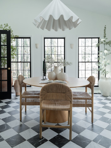 Green Ridge sunroom with black-and-white checkered floors, black-trimmed large windows, wood table and chairs with vases, and a white ballerina pendant lamp, creating a bright, elevated, and stylish space. Located in Marietta, Georgia.