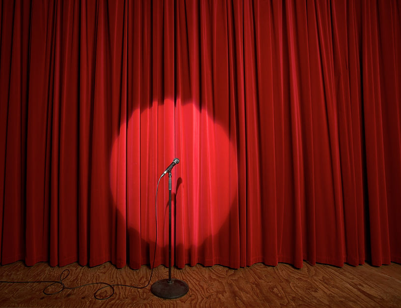 Microphone on stage in front of red curtain