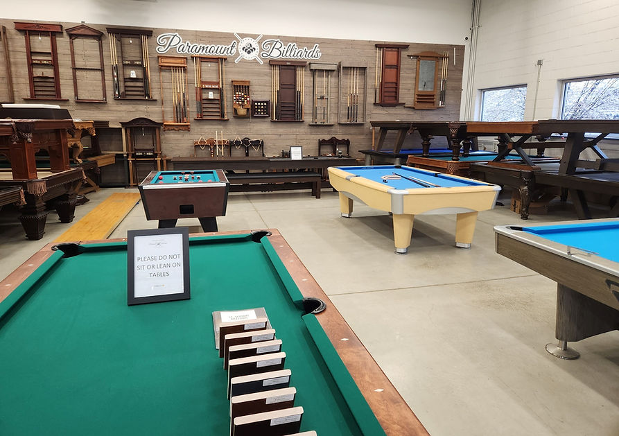 Premium billiards table with rich green felt in a luxury game room — warm ambient lighting, dark wood frame