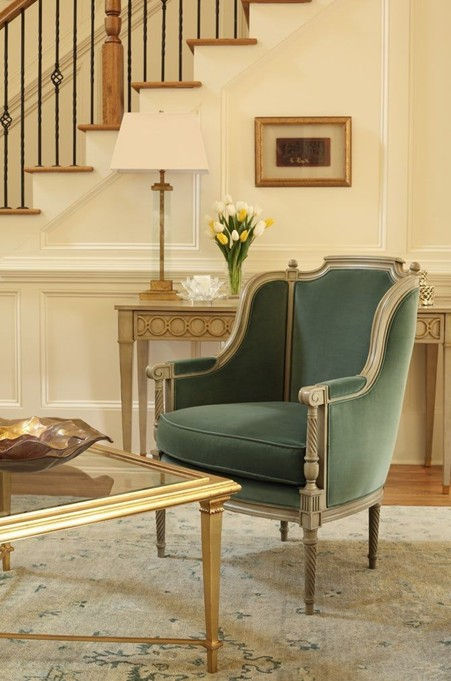 Handcrafted claw-foot table and tufted sofa with gold accents in a classic neo-classical setting.