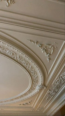 Coffered ceiling with ornate medallion and chandelier in an elegant neo-classical dining room.