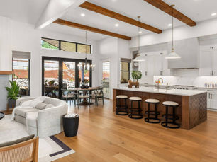 Modern kitchen interior design connected to a spacious hall with earthy tones, modular cabinets, and stylish lighting.