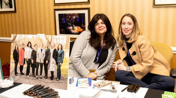 Two women at conference table with group photo
