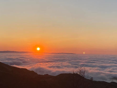 A photograph of the sunset from the top of a mountain, the canyon is blocked from view by dense clouds or fog