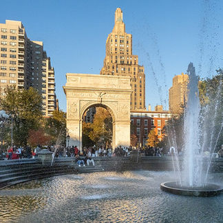 The festive community Christmas tree standing in the center of Washington Square Park plaza, surrounded by historic Greenwich Village townhouses during the winter season.