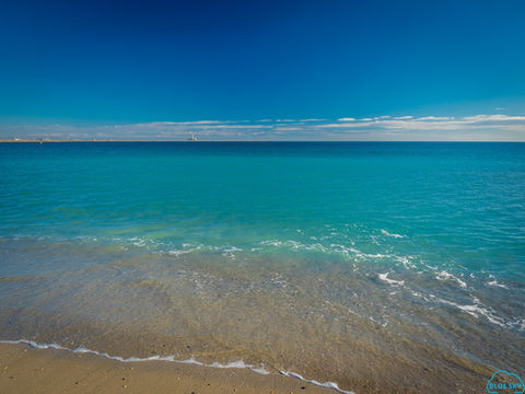 Plajă cu nisip în Eforie Nord și valuri liniștite sub un cer senin