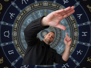 Bran Alder in front of a zodiac wheel background with symbols. Dark colors, mystical vibe.