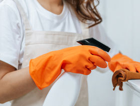 Professional cleaner spraying cloth during regular cleaning service