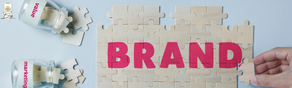 Hand places puzzle piece with word "BRAND" on light blue surface; jars labeled "value" and "marketing" with puzzle pieces spill contents.