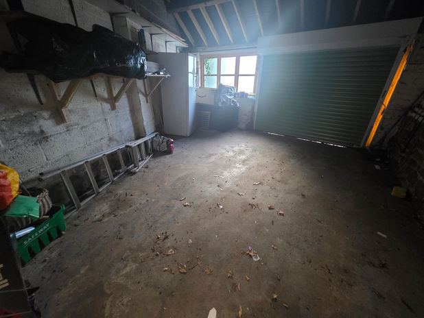 Garage before clearance showing stored household items and waste.