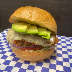 Delicious burger with avocado and cheese on a blue and white checkered cloth