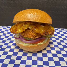 Delicious chicken sandwich with toppings, presented on a blue checkered background.