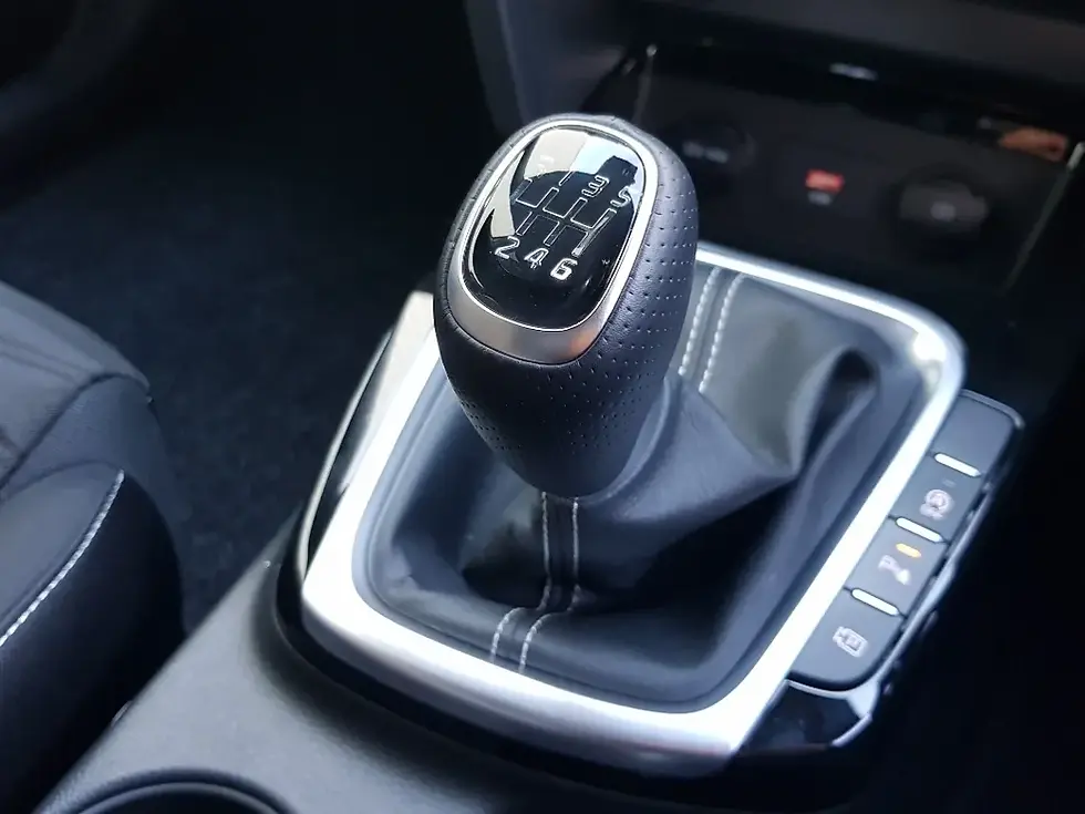 Close up of a manual transmission gear stick set in the centre console, with the gear pattern clearly visible on the top of the knob.