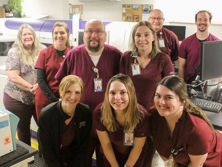 Lab staff with new chemistry analyzer behind them.