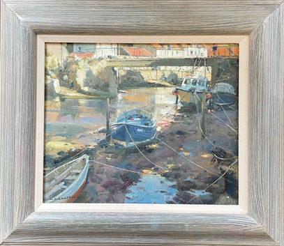A view from Staithes Beck riverbed at low tide, the beached boats in shadow while the water and background cottages in the top left side of the painting are bathed in dazzling golden light.