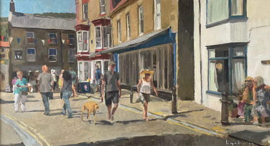 A tranquil moment on the corner of Staithes High Street with visitors enjoying the late afternoon heat as they walk past Staithes shopfronts.