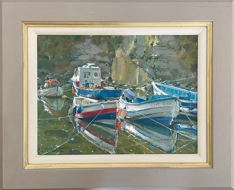 A tranquil moment in Staithes Beck depicting several wooden fishing boats sitting on the calm water.